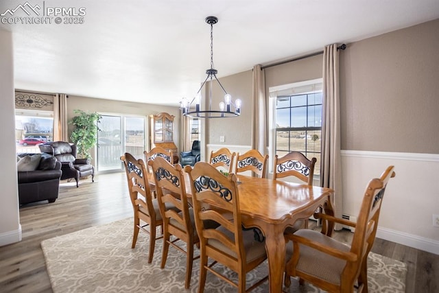 dining area with a wealth of natural light, baseboards, light wood finished floors, and a notable chandelier