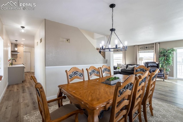 dining space with baseboards, light wood-style flooring, a chandelier, and a wealth of natural light