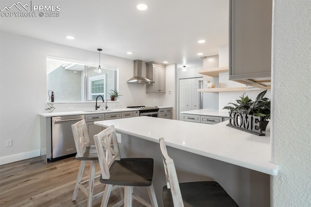 kitchen with open shelves, gray cabinetry, appliances with stainless steel finishes, a peninsula, and wall chimney exhaust hood