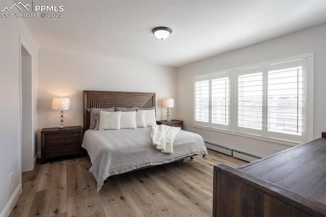 bedroom with light wood finished floors and baseboard heating