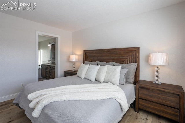 bedroom featuring ensuite bath, baseboards, and wood finished floors