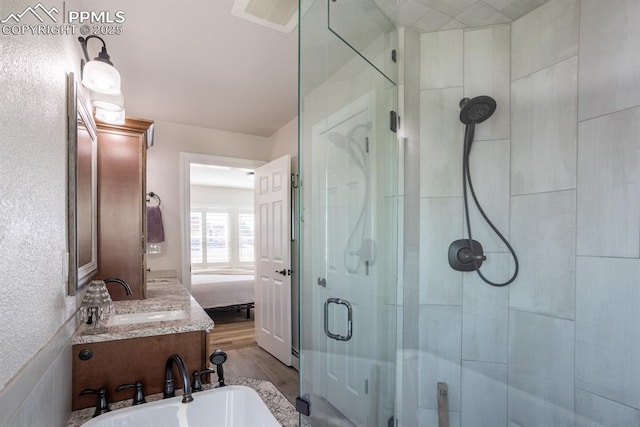 ensuite bathroom featuring a washtub, ensuite bathroom, a stall shower, a sink, and wood finished floors