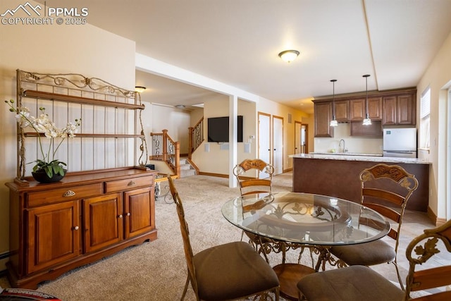 dining area with stairs, baseboards, and light colored carpet