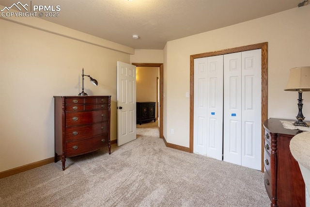 bedroom with baseboards, a closet, and light colored carpet