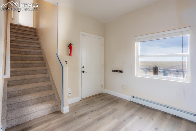 entrance foyer featuring light wood-type flooring, a baseboard radiator, stairway, and baseboards