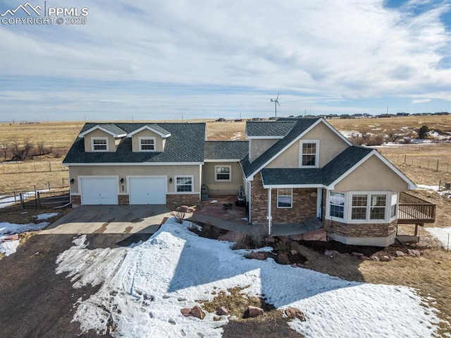 view of front of house with driveway, stone siding, fence, and stucco siding