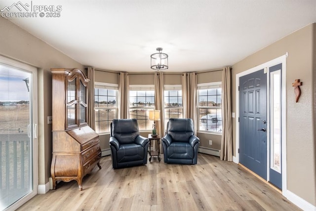 living area featuring light wood-style floors, baseboards, and baseboard heating