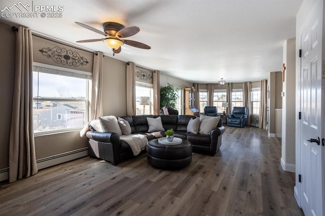 living room with a ceiling fan, a baseboard heating unit, baseboards, and wood finished floors