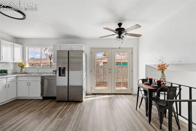 kitchen featuring stainless steel appliances, french doors, white cabinetry, and light wood-style floors