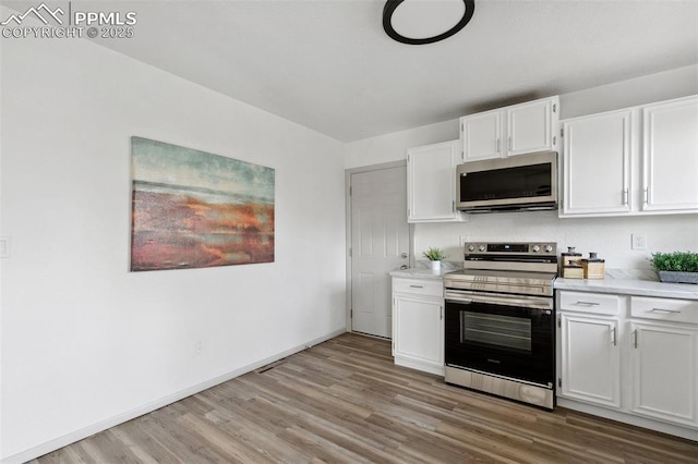 kitchen with stainless steel appliances, white cabinetry, baseboards, light wood-style floors, and light countertops