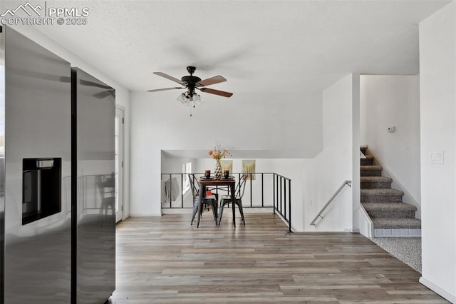 dining room featuring ceiling fan, wood finished floors, and stairs