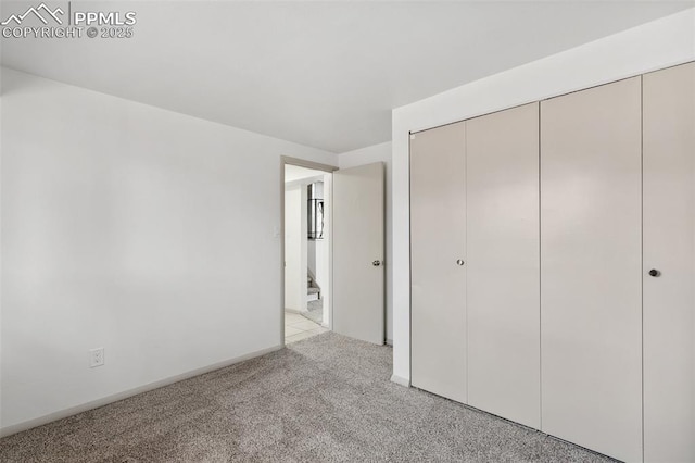 unfurnished bedroom with baseboards, a closet, and light colored carpet