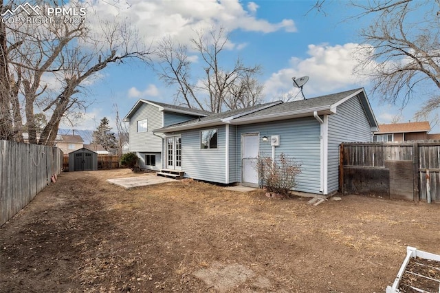 rear view of house featuring entry steps, a storage unit, an outbuilding, and a fenced backyard