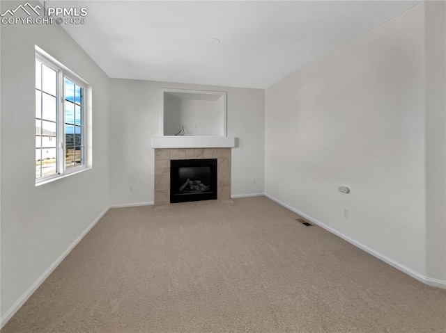 unfurnished living room with carpet floors, visible vents, a fireplace, and baseboards