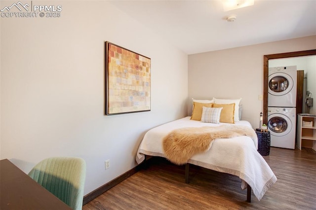 bedroom with stacked washer / drying machine, baseboards, and wood finished floors