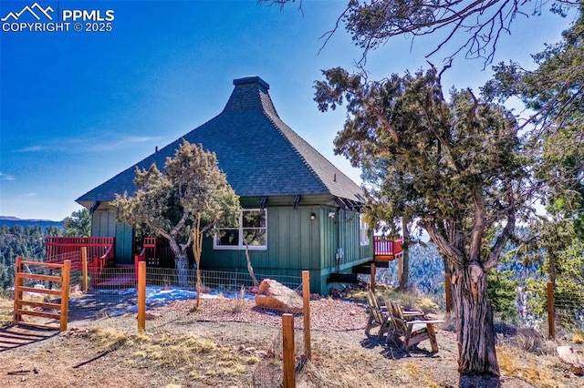 view of side of home featuring a shingled roof and fence