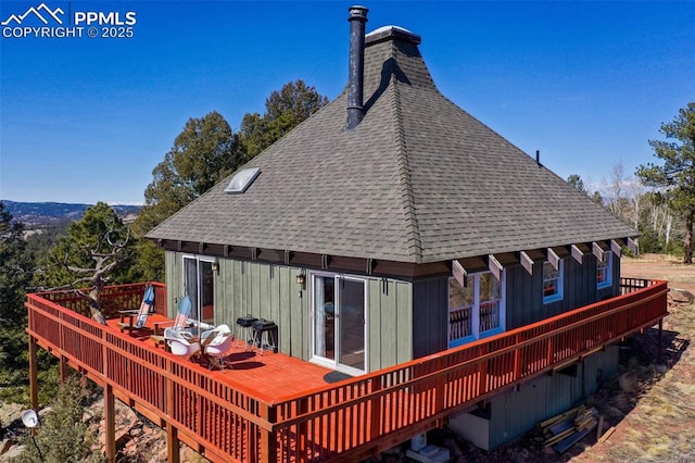 back of house featuring board and batten siding, roof with shingles, and a wooden deck