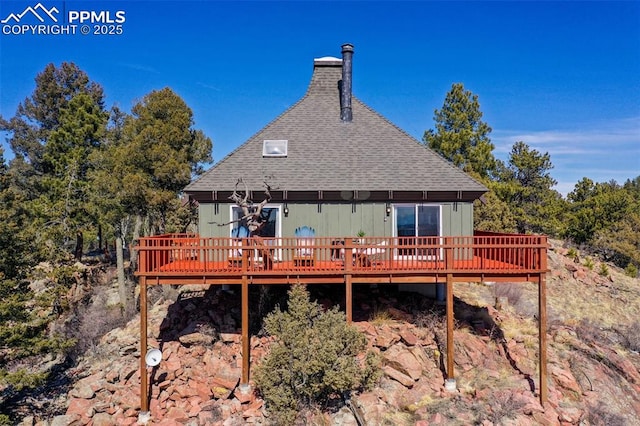 rear view of house with a deck and roof with shingles