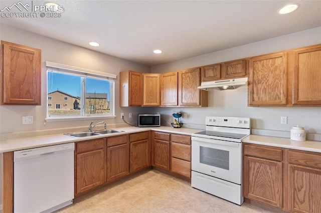 kitchen featuring white appliances, under cabinet range hood, light countertops, and a sink