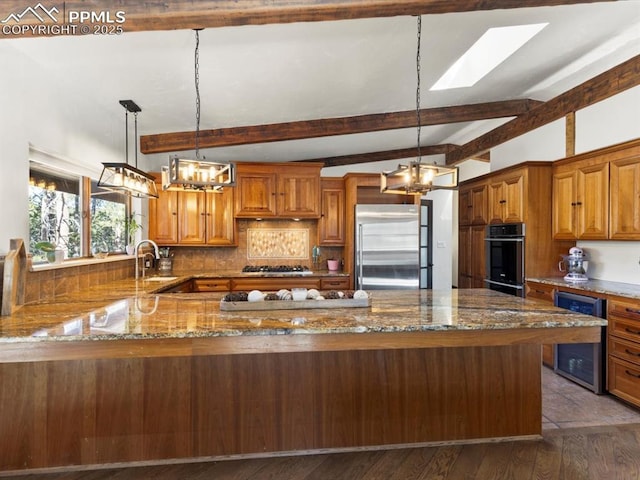 kitchen with appliances with stainless steel finishes, wine cooler, stone countertops, and brown cabinetry