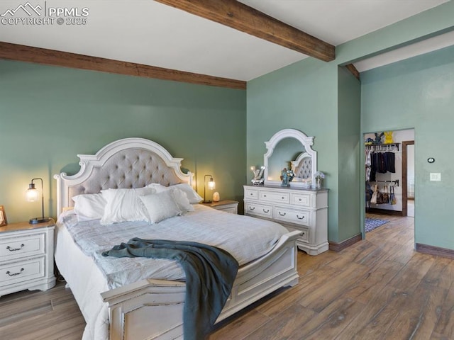 bedroom featuring wood finished floors, beam ceiling, and baseboards