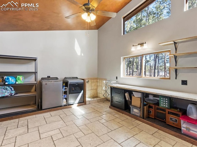 interior space with refrigerator, a ceiling fan, a towering ceiling, independent washer and dryer, and stone tile flooring