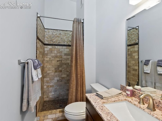 bathroom with a tile shower, vanity, and toilet