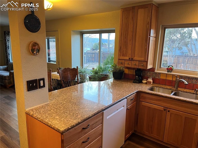 kitchen with dark wood finished floors, white dishwasher, a sink, and light stone countertops