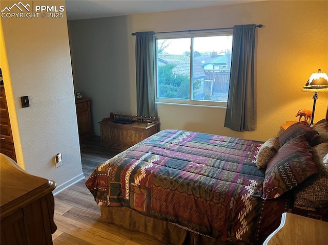 bedroom with baseboards and wood finished floors