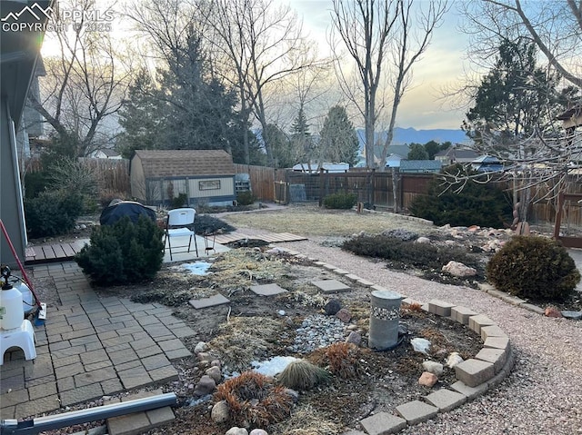 view of yard with a patio area, a fenced backyard, an outbuilding, and a shed