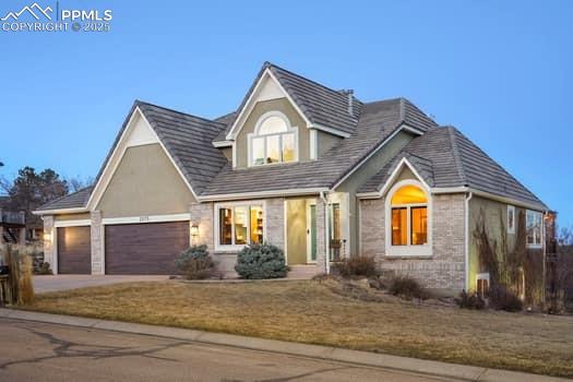 view of front of house with driveway, stone siding, an attached garage, and a front yard