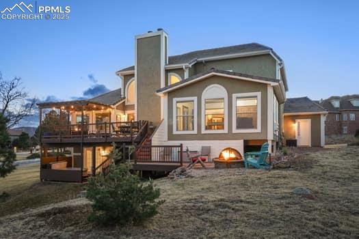 rear view of property with a deck, an outdoor fire pit, and a chimney