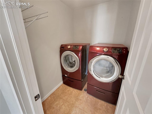 laundry area with laundry area, light tile patterned flooring, washing machine and clothes dryer, and baseboards