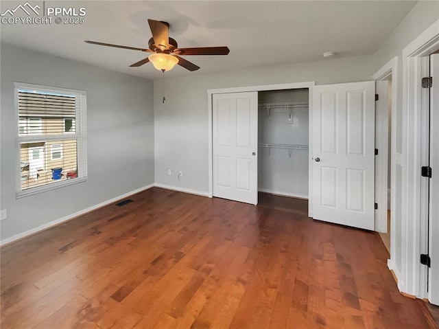 unfurnished bedroom featuring a closet, visible vents, ceiling fan, wood finished floors, and baseboards