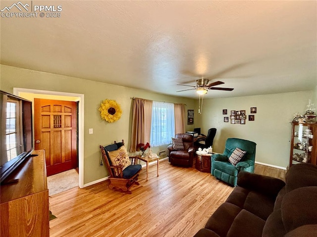 living area with baseboards, ceiling fan, and light wood finished floors