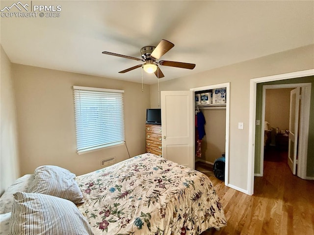 bedroom with a closet, wood finished floors, a ceiling fan, and baseboards