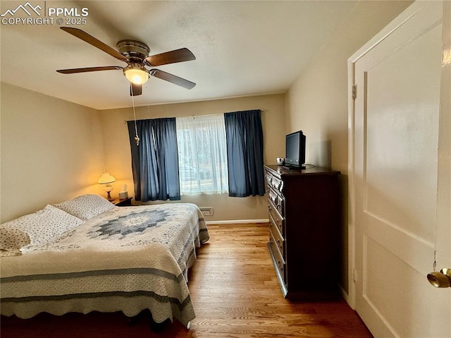 bedroom featuring ceiling fan, baseboards, and wood finished floors