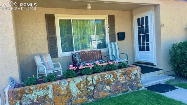 entrance to property with a porch and stucco siding