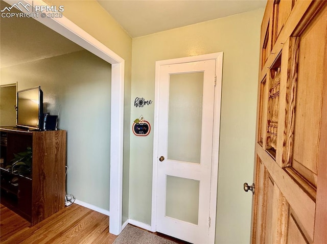 hallway featuring wood finished floors and baseboards