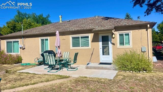 rear view of house with a patio, a lawn, and stucco siding