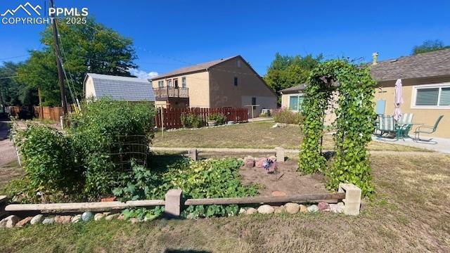 view of yard with a vegetable garden, fence, an outbuilding, and a storage shed