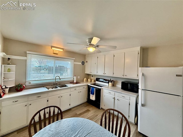 kitchen with electric stove, freestanding refrigerator, white cabinetry, a sink, and black microwave