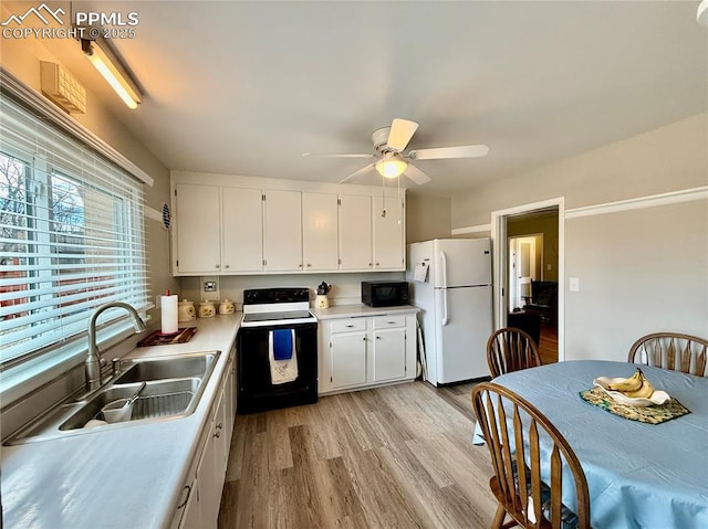 kitchen featuring black microwave, a sink, electric stove, light countertops, and freestanding refrigerator