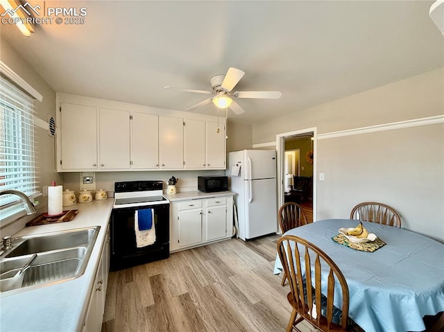 kitchen featuring electric stove, light countertops, freestanding refrigerator, a sink, and black microwave