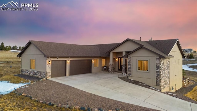 view of front of home featuring a garage, concrete driveway, stone siding, roof with shingles, and stucco siding