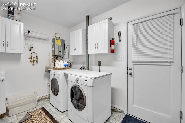 washroom featuring cabinet space, baseboards, tankless water heater, and washer and dryer