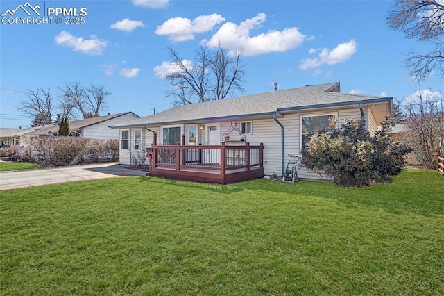 rear view of property with roof with shingles, a lawn, and a deck