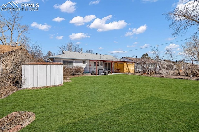 back of house featuring an outbuilding, a lawn, a patio, and a shed