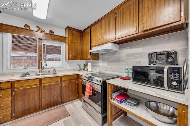 kitchen featuring stainless steel electric range oven, brown cabinets, a sink, and under cabinet range hood