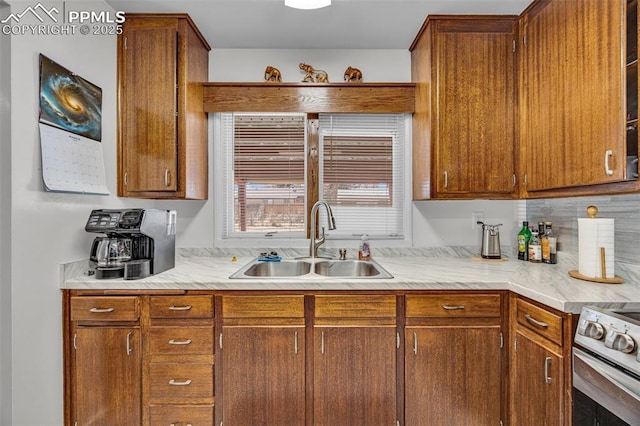 kitchen with light countertops, electric range, a sink, and brown cabinets